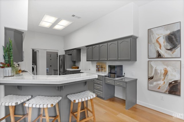 6707 Park W Cir, Bakersfield, CA 93308 - kitchen featuring gray cabinets, light wood-style flooring, and a breakfast bar