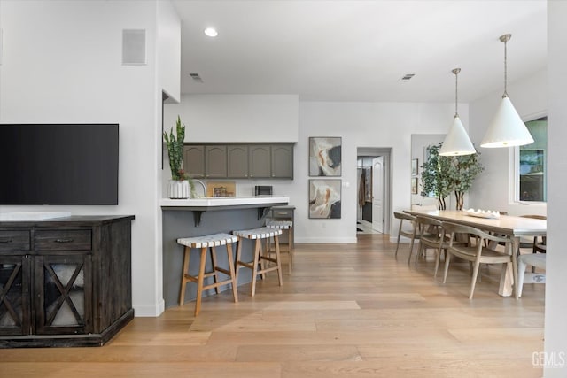 6707 Park W Cir, Bakersfield, CA 93308 - kitchen featuring a kitchen bar, light wood-style floors, light countertops, hanging light fixtures, and a peninsula