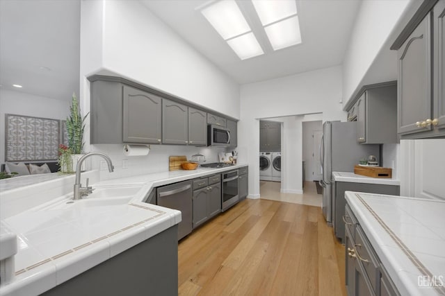 6707 Park W Cir, Bakersfield, CA 93308 - kitchen with independent washer and dryer, tile counters, gray cabinetry, light wood finished floors, and recessed lighting