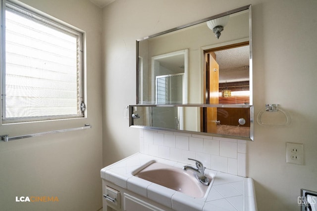 bathroom featuring an enclosed shower, a sink, a healthy amount of sunlight, and backsplash