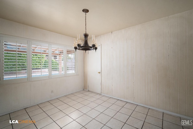 unfurnished dining area featuring a notable chandelier, wood walls, and light tile patterned floors