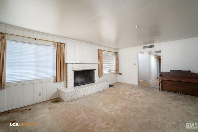 unfurnished living room with visible vents, carpet flooring, and a brick fireplace