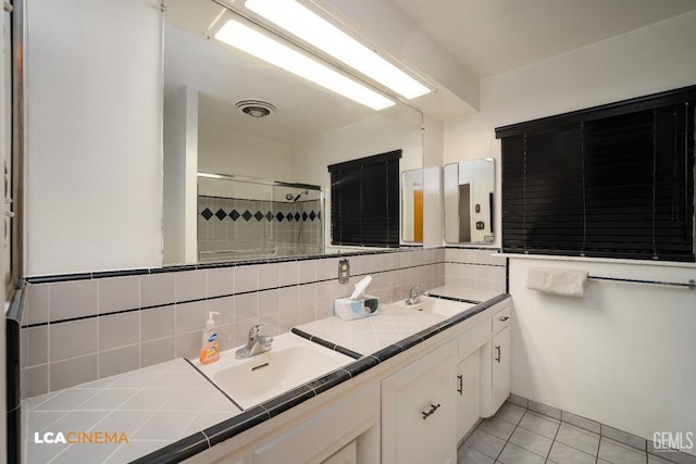 full bathroom featuring tile patterned floors, a sink, a stall shower, and double vanity