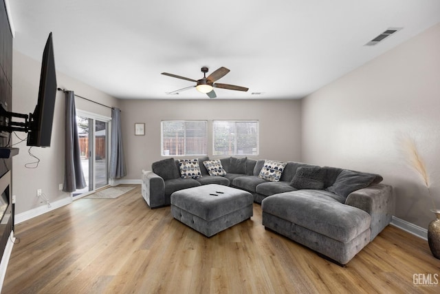 living area with light wood-style floors, baseboards, visible vents, and ceiling fan