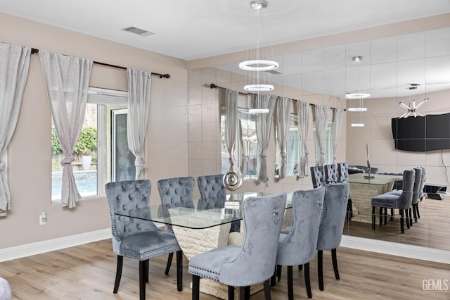 dining room featuring light wood finished floors, visible vents, and baseboards