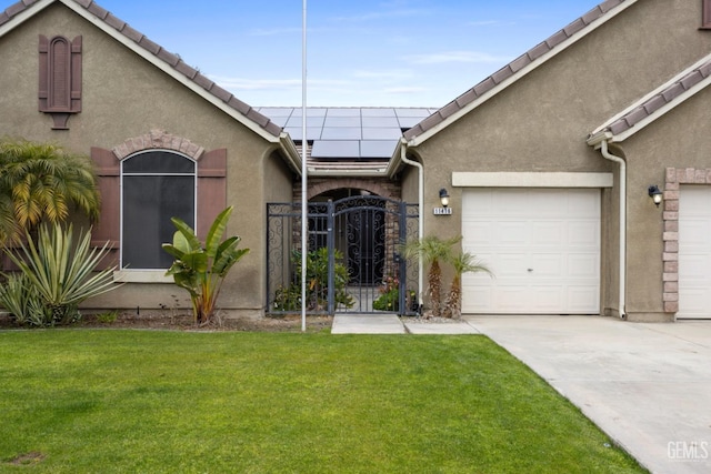 view of front of property with a garage, stucco siding, a gate, roof mounted solar panels, and a front yard