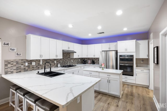 kitchen with visible vents, appliances with stainless steel finishes, a sink, a peninsula, and under cabinet range hood