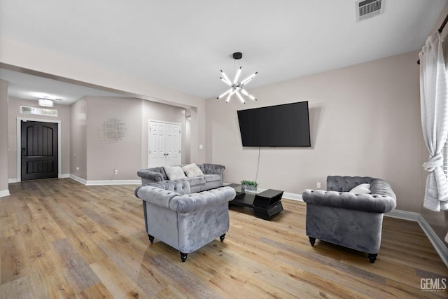 living room featuring baseboards, an inviting chandelier, visible vents, and light wood-style floors