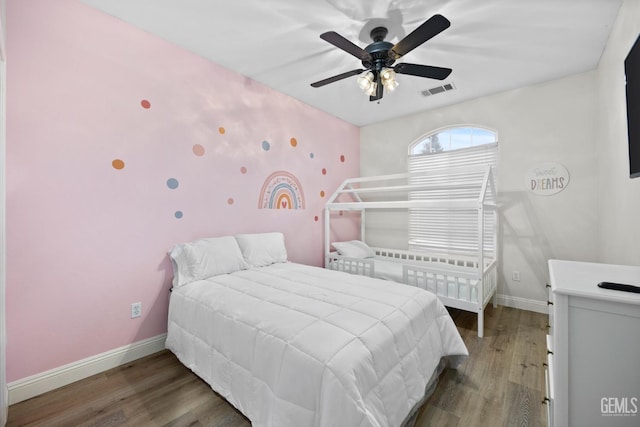 bedroom featuring ceiling fan, wood finished floors, visible vents, and baseboards