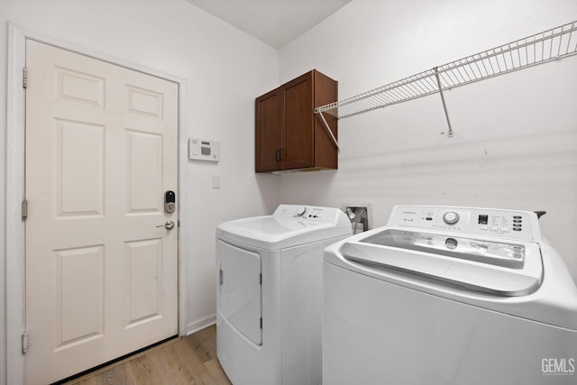 washroom with cabinet space, light wood-style flooring, and independent washer and dryer