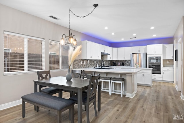 dining area with visible vents, baseboards, light wood-style flooring, an inviting chandelier, and recessed lighting