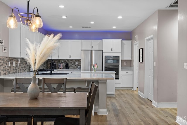 kitchen featuring dobule oven black, stainless steel fridge, visible vents, white cabinetry, and a sink