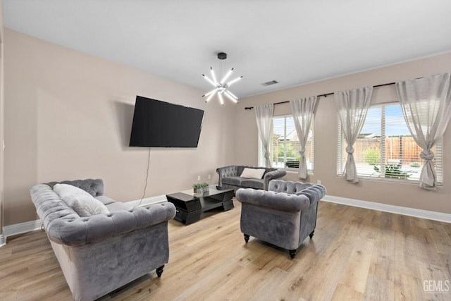 living area with light wood-type flooring, baseboards, visible vents, and a notable chandelier