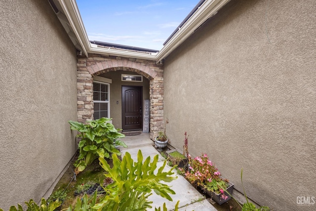 property entrance featuring stone siding and stucco siding