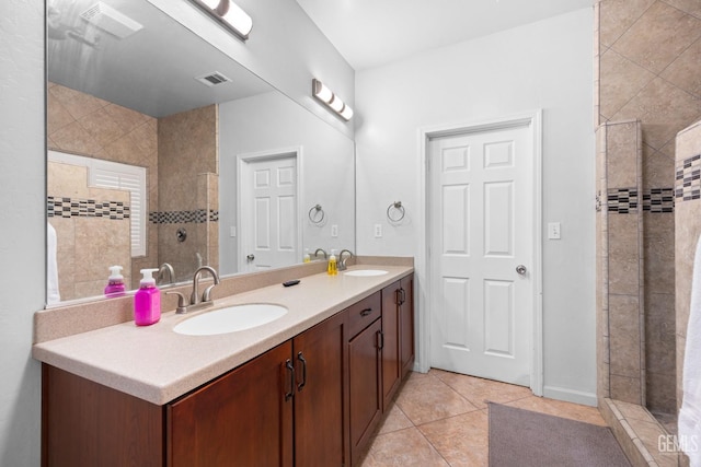 bathroom with a tile shower, a sink, visible vents, and tile patterned floors