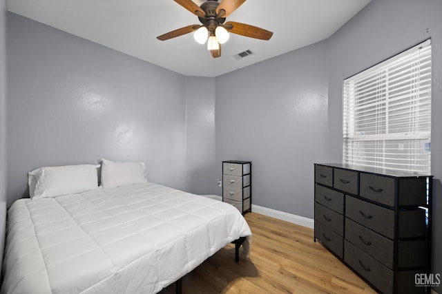 bedroom featuring baseboards, ceiling fan, visible vents, and light wood finished floors