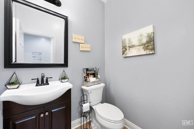 bathroom with toilet, baseboards, and vanity