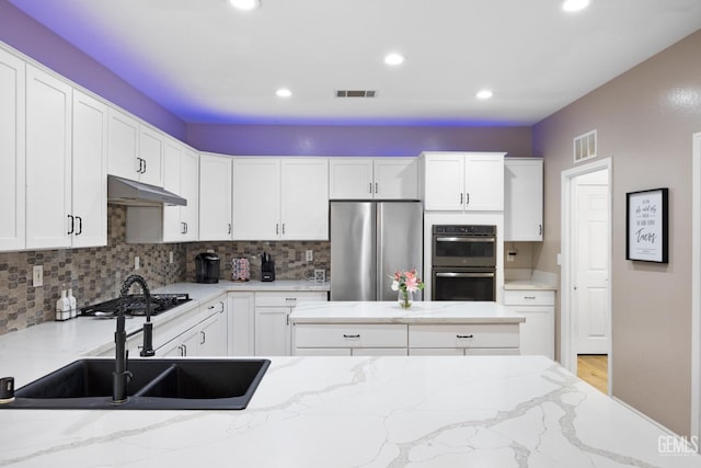 kitchen featuring visible vents, double oven, a sink, and freestanding refrigerator