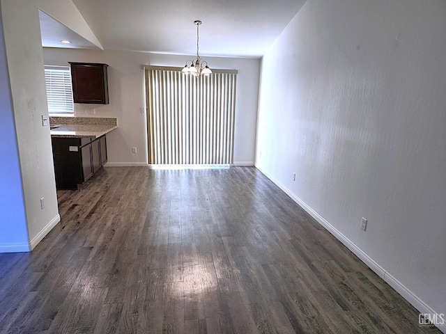 unfurnished dining area with dark wood-type flooring, vaulted ceiling, and a notable chandelier