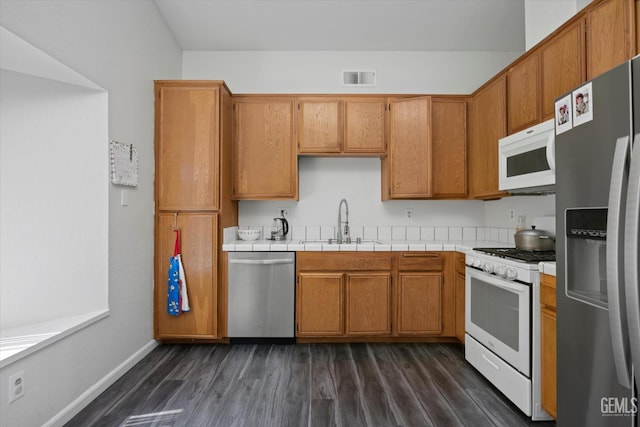 4715 Peacock Ct, Bakersfield, CA 93313 - kitchen featuring appliances with stainless steel finishes, a sink, dark wood-style floors, brown cabinets, and baseboards
