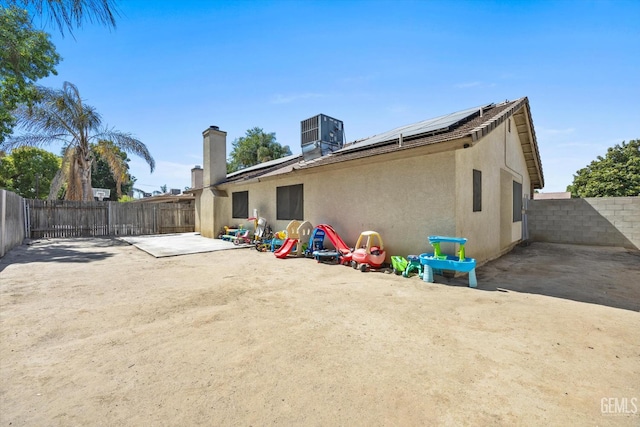 4715 Peacock Ct, Bakersfield, CA 93313 - back of house featuring stucco siding, a chimney, a patio area, roof mounted solar panels, and a fenced backyard