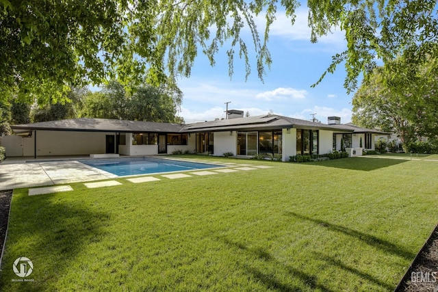 2221 Myrtle St, Bakersfield, CA 93301 - back of house featuring an outdoor pool, roof mounted solar panels, a lawn, and a patio