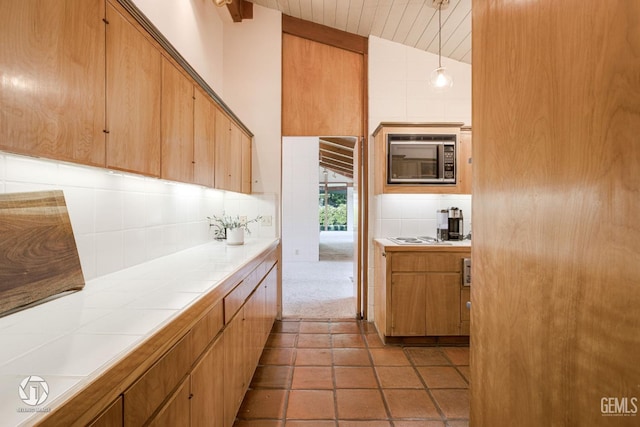 2221 Myrtle St, Bakersfield, CA 93301 - kitchen with stainless steel microwave, lofted ceiling, tile counters, and decorative backsplash