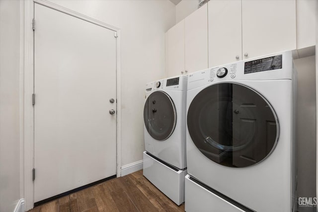 clothes washing area featuring separate washer and dryer, dark wood-style flooring, cabinet space, and baseboards