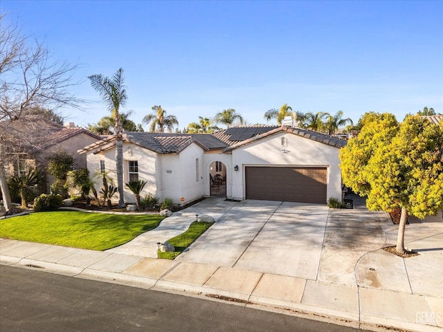 mediterranean / spanish-style home featuring an attached garage, a tile roof, a front lawn, and stucco siding