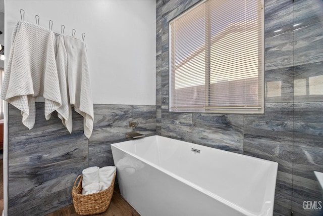 full bath with tile walls and a freestanding bath