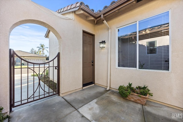 entrance to property with a patio area, a tile roof, and stucco siding