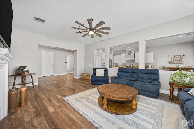 living area with baseboards, wood finished floors, visible vents, and a ceiling fan