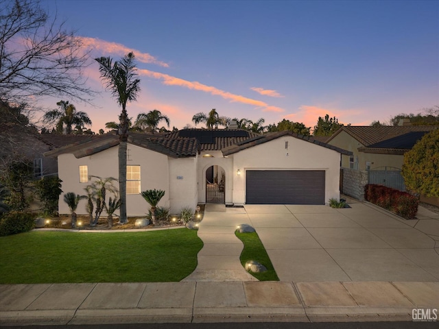 mediterranean / spanish-style house featuring roof mounted solar panels, a gate, fence, and stucco siding