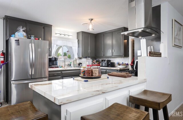 109 Bermuda St, Bakersfield, CA 93309 - kitchen with freestanding refrigerator, island exhaust hood, a peninsula, decorative backsplash, and light stone countertops