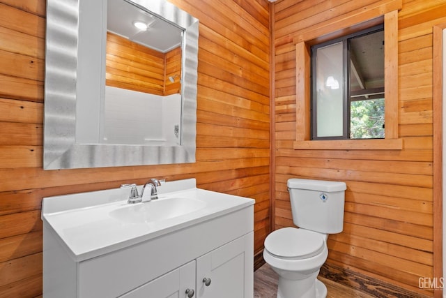 bathroom featuring vanity, toilet, and wooden walls