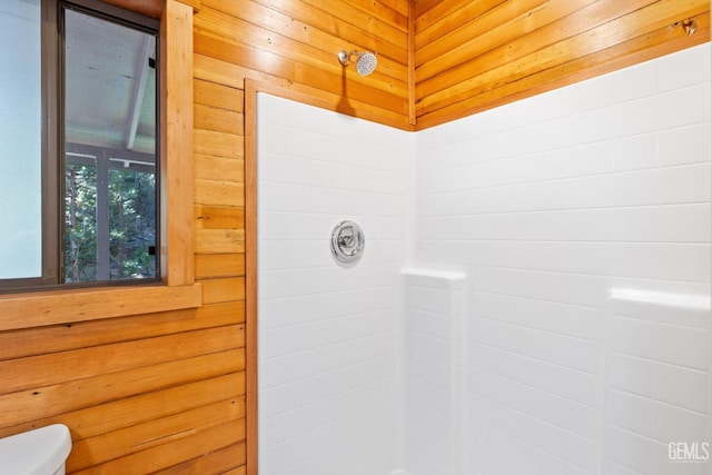 bathroom with wood walls, toilet, and walk in shower