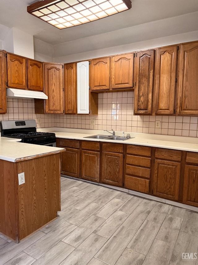 1107 Monterey St, Bakersfield, CA 93305 - kitchen featuring stainless steel gas range, under cabinet range hood, light wood-type flooring, light countertops, and brown cabinets
