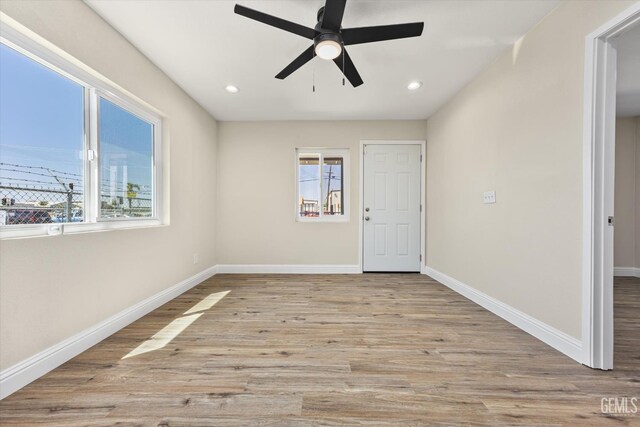 spare room featuring plenty of natural light, ceiling fan, wood finished floors, baseboards, and recessed lighting