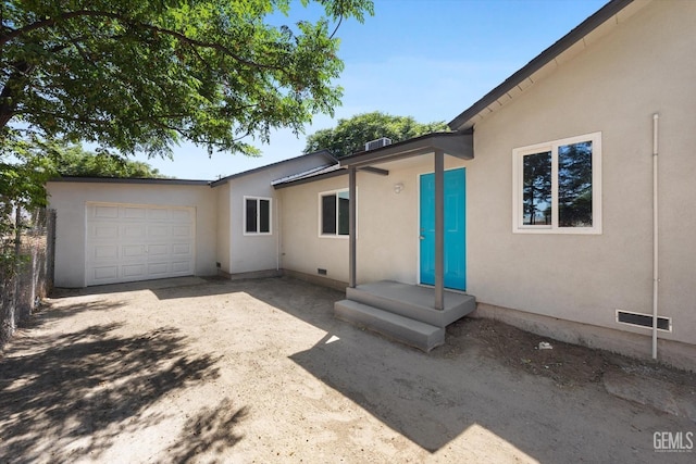 view of side of home with crawl space, an attached garage, concrete driveway, and stucco siding