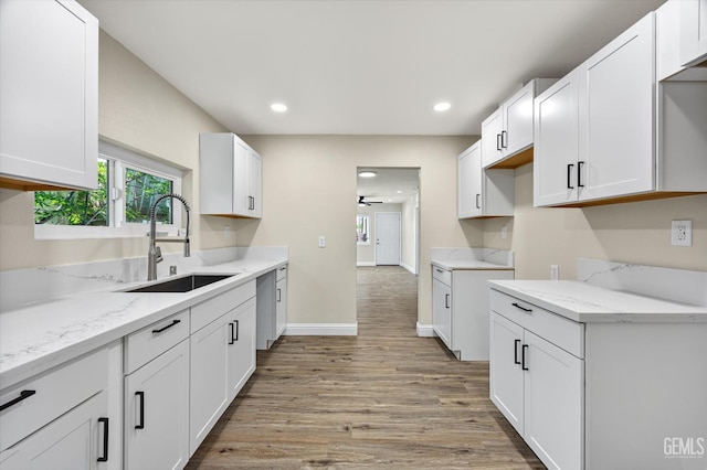 kitchen featuring a sink, ceiling fan, light wood finished floors, light stone counters, and recessed lighting