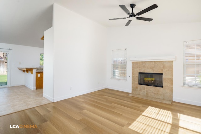6905 Gwenivere Ct, Bakersfield, CA 93313 - unfurnished living room featuring a tile fireplace, a ceiling fan, plenty of natural light, and light wood-style flooring