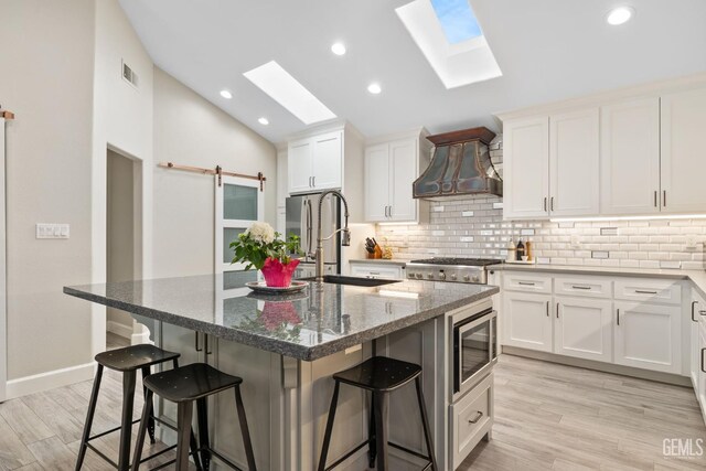 8220 Birmingham St, Bakersfield, CA 93311 - kitchen featuring appliances with stainless steel finishes, premium range hood, a skylight, backsplash, and vaulted ceiling