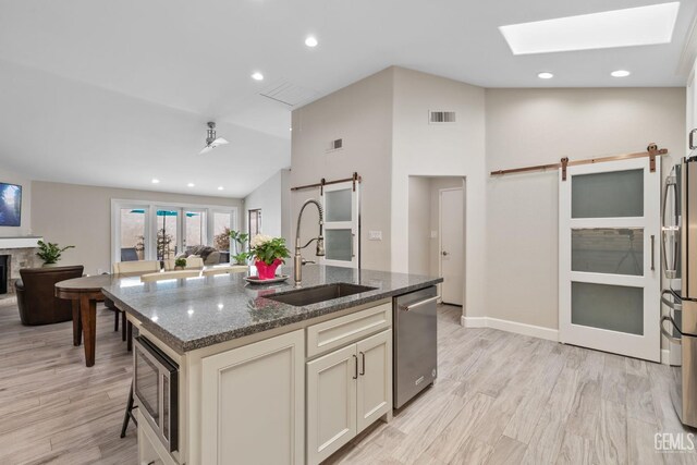 8220 Birmingham St, Bakersfield, CA 93311 - kitchen featuring a barn door, a sink, stainless steel appliances, dark stone counters, and lofted ceiling
