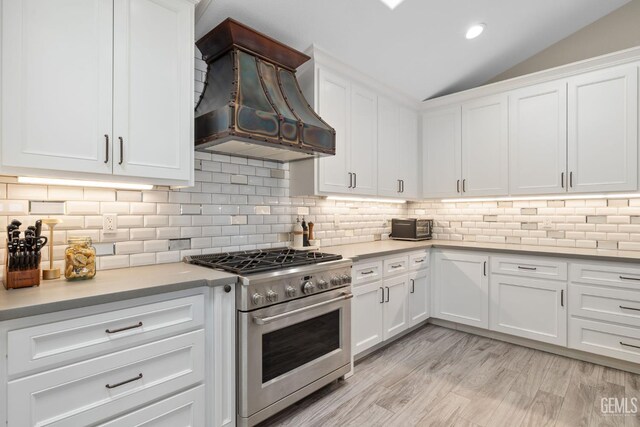 8220 Birmingham St, Bakersfield, CA 93311 - kitchen featuring stainless steel stove, custom exhaust hood, white cabinetry, light countertops, and lofted ceiling