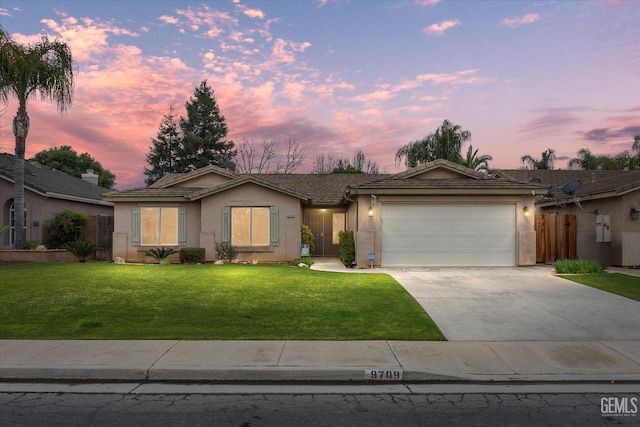 ranch-style home featuring a garage and a yard