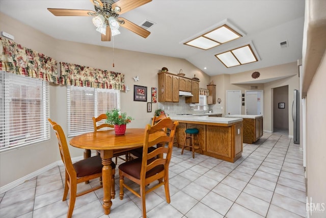 tiled dining room featuring ceiling fan and vaulted ceiling