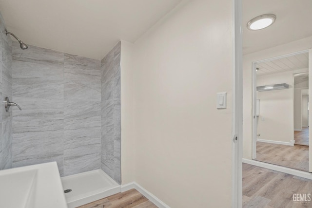 bathroom featuring hardwood / wood-style flooring and a tile shower