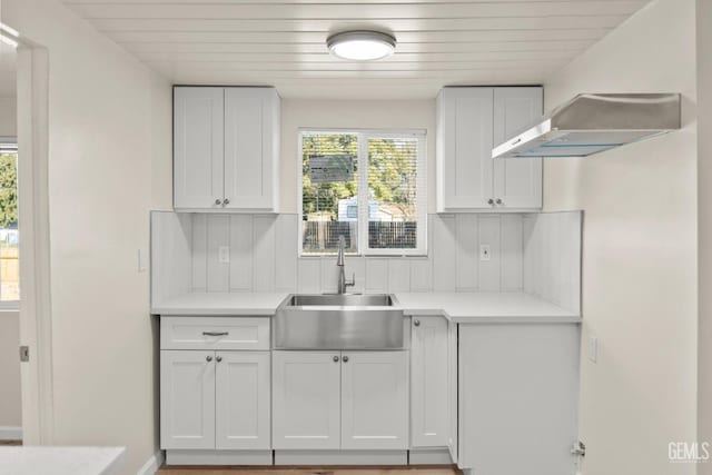 kitchen featuring backsplash, white cabinetry, sink, and wall chimney exhaust hood