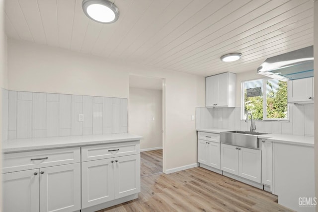 kitchen with white cabinets, light hardwood / wood-style floors, sink, and extractor fan