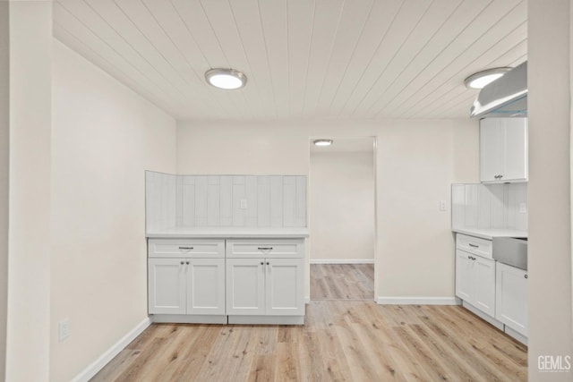 kitchen with decorative backsplash, white cabinets, and light hardwood / wood-style floors